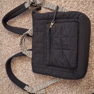 Black quilted nylon backpack with black and white handles and straps